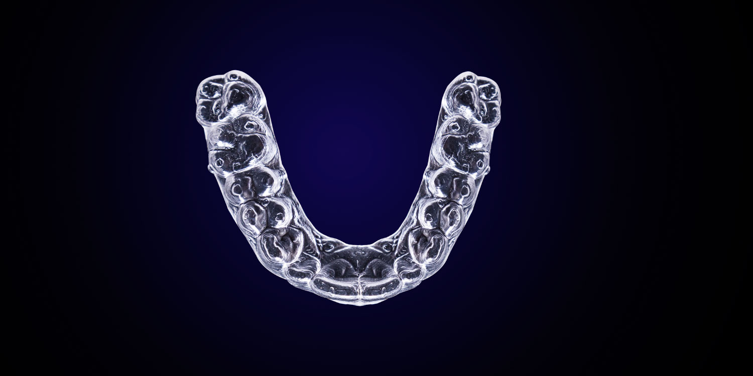 Aerial view of a clear aligner tray against a navy background