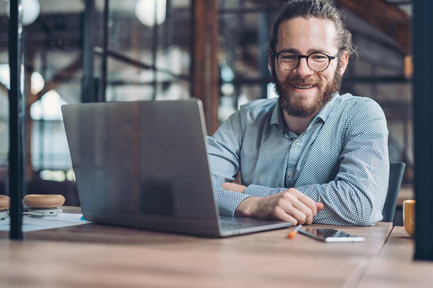 Adult business man with a laptop smiles while wearing braces as an adult